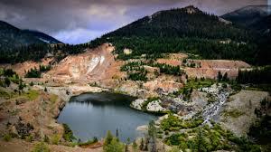 lake surrounded by mountains under a cloudy sky near an antimony mine