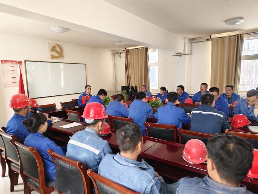 group of people sitting at desks in front of a projector screen with rare earth polishing powders displayed on the table