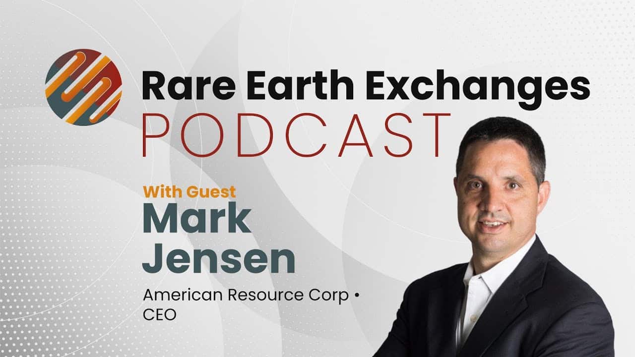 man in a suit and tie standing in front of a sign related to the rare earth supply chain
