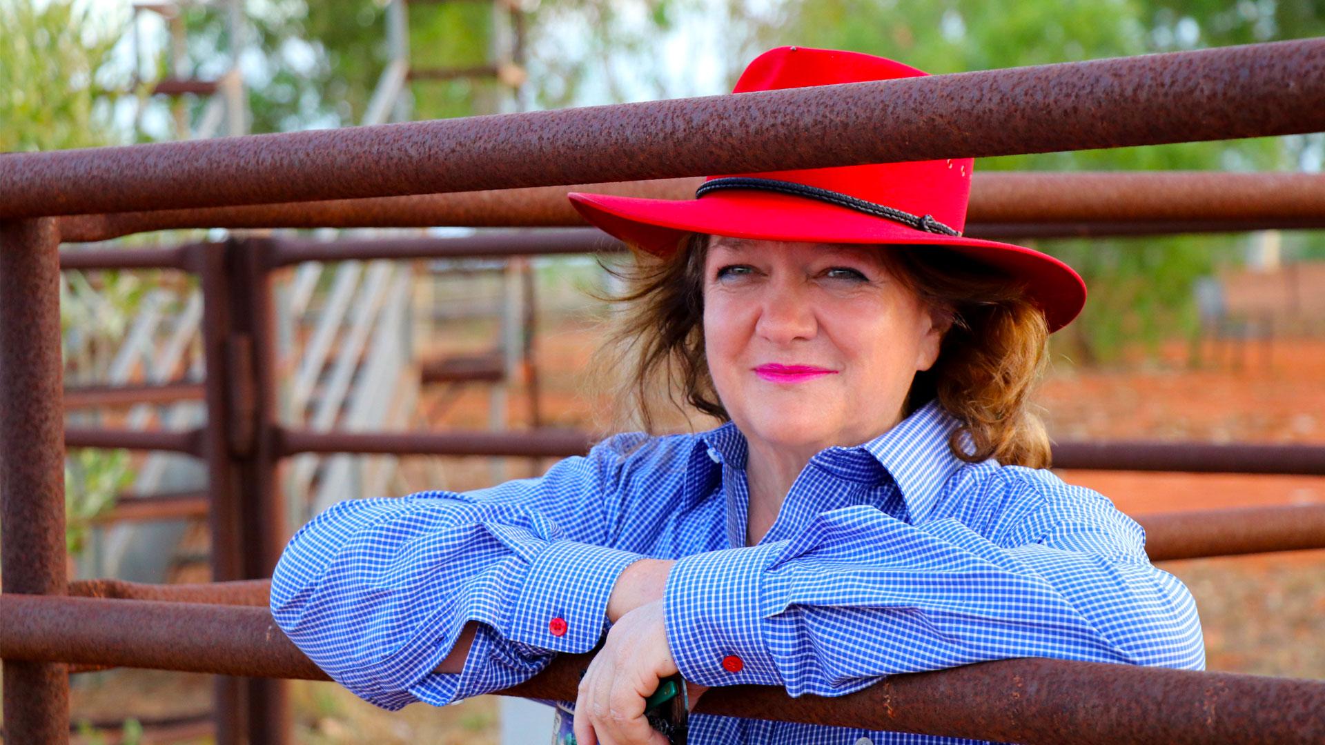 woman wearing a red hat leaning on a fence, MP Materials