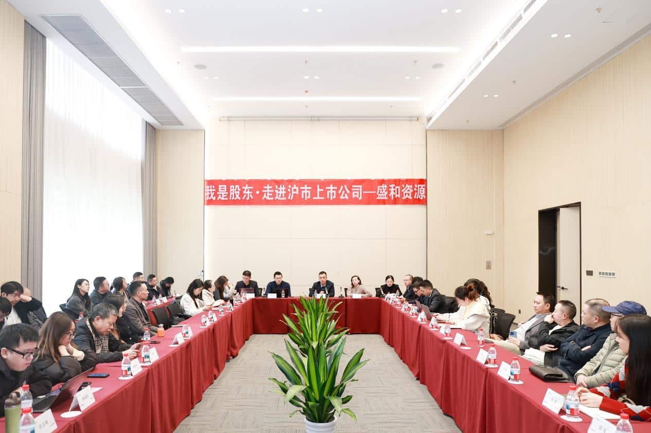 group of people sitting at long tables with Shenghe Resources branding