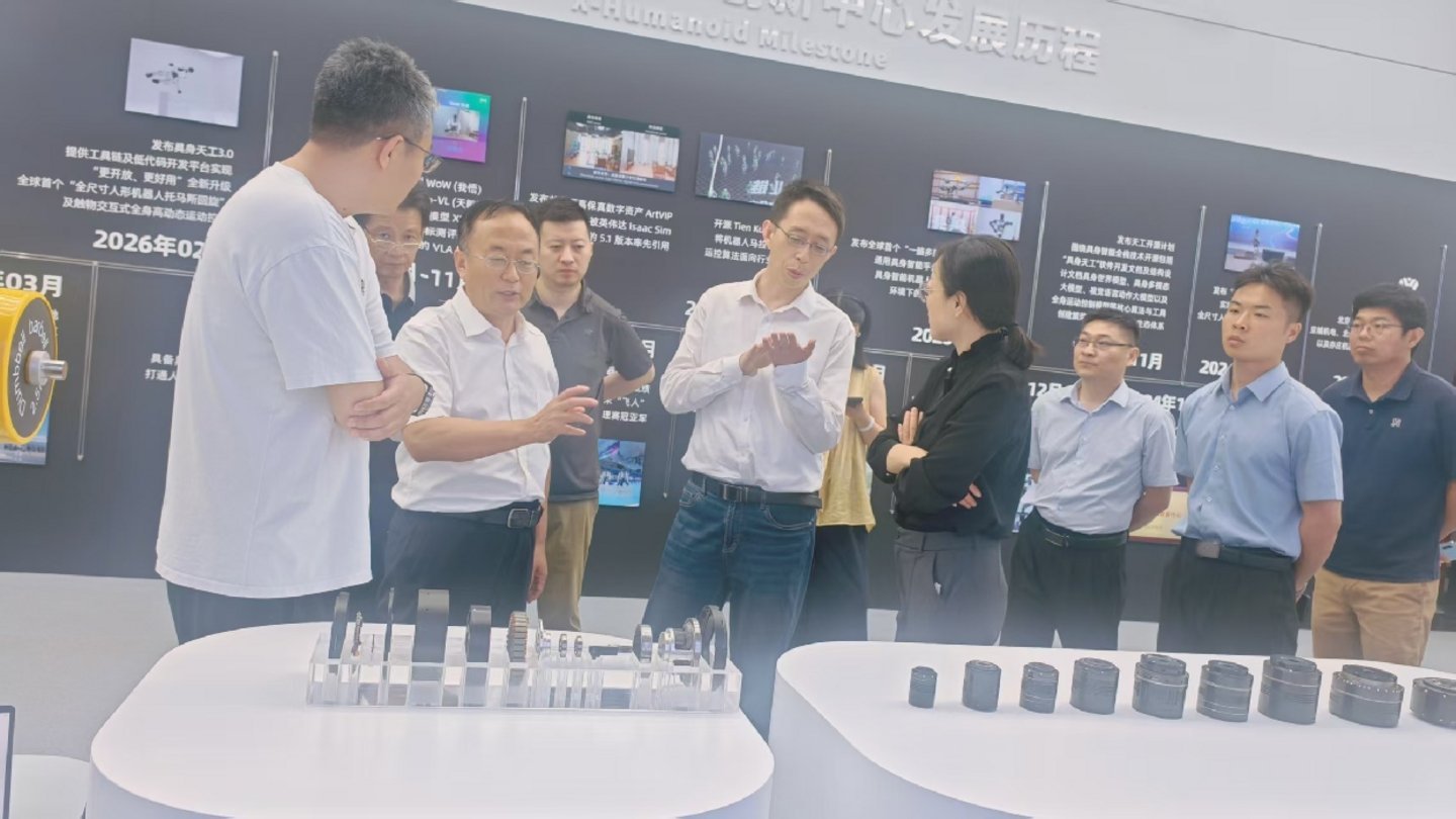Group of professionals examining humanoid robot actuator components at X-Humanoid Milestone development center exhibition in