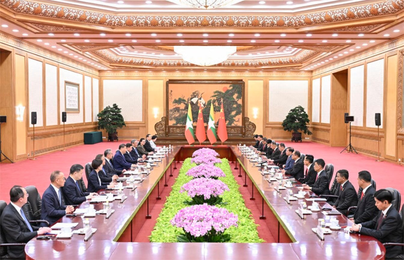 High-level diplomatic meeting between Chinese and Myanmar delegations at ornate conference table with Chinese and Myanmar fla