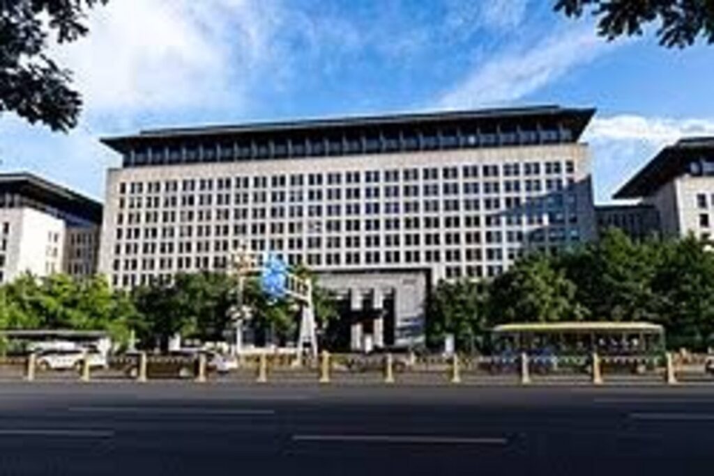 Multistory beige government administrative building with traditional Chinese roofline in Beijing along a wide urban boulevard