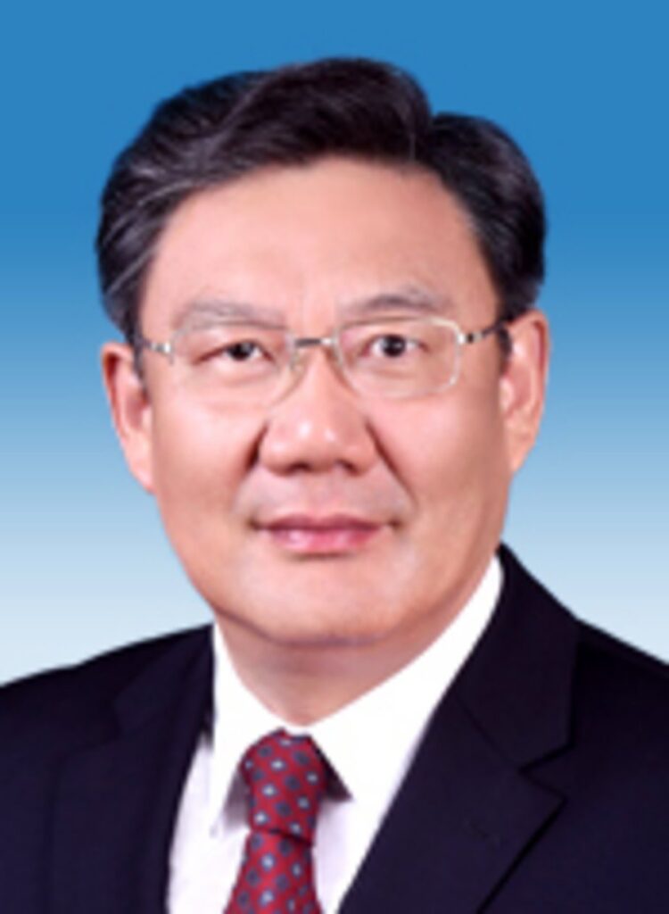 Middle-aged Asian man in dark business suit with white dress shirt and red patterned tie, wearing wire-rimmed glasses, formal