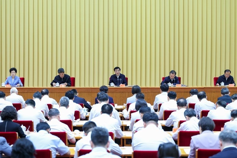 Senior Chinese Communist Party officials seated at presidium table addressing delegates in formal government conference hall