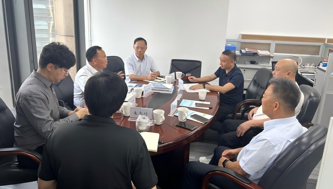 Seven professionals in formal business meeting around oval wooden table with name placards including Zhu Dongzhu in modern Ch