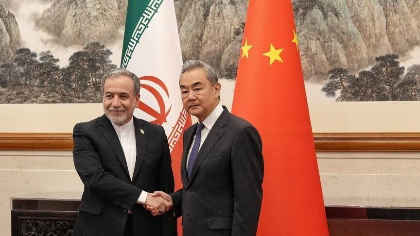 Two diplomats shaking hands in front of the Iranian tricolor flag and Chinese red five-star flag with landscape painting back