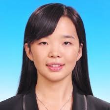 Young East Asian woman with straight black bangs, wearing a dark blazer and delicate necklace, formal professional portrait o