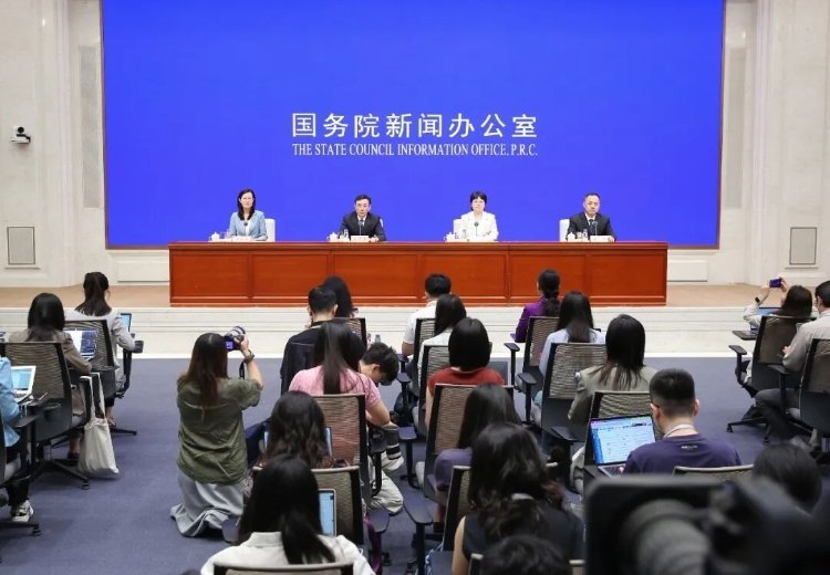 Four officials seated at podium during State Council Information Office P.R.C. press briefing in Beijing with journalists att