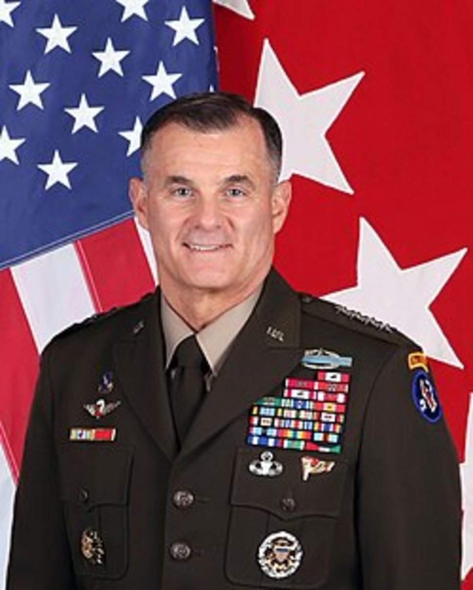 Senior US Army General in dress green uniform with multiple service ribbons, medals, and aviator wings before American and ge
