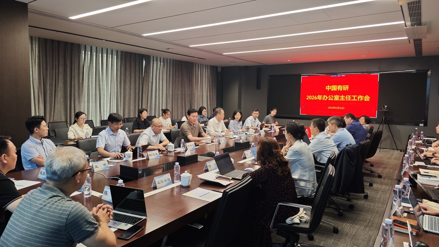 China Youyan executives and office directors seated at large boardroom table during 2026 annual work conference, red presenta