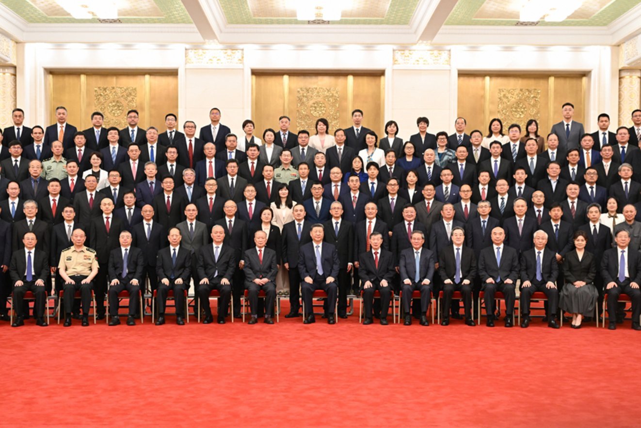 Large formal group of Chinese government officials and dignitaries seated and standing in rows at the Great Hall of the Peopl