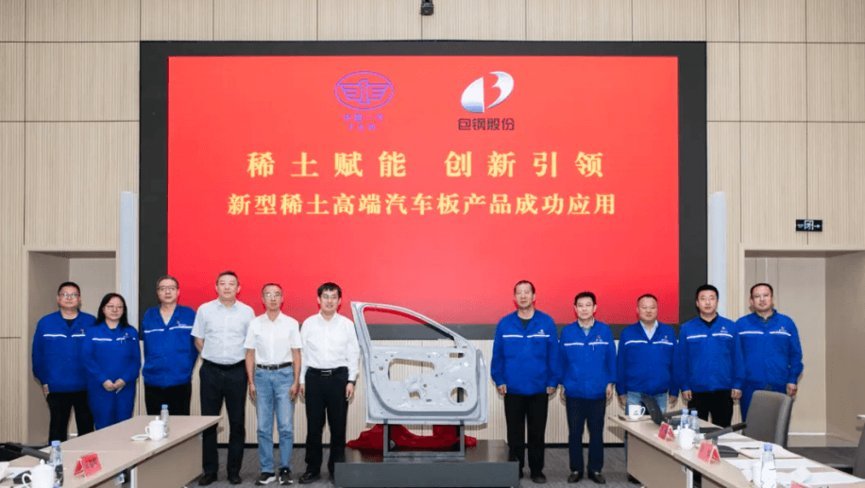 Group of executives and workers in blue uniforms at Baotou Steel rare earth automotive panel success application event with r