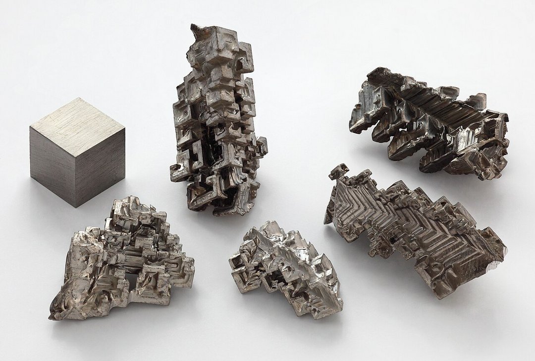 Pure osmium element 76 displaying one machined cubic sample alongside five naturally grown dendritic crystalline formations o