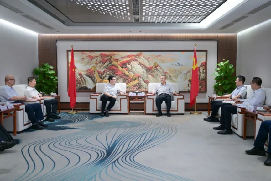 Senior Chinese officials in formal bilateral meeting, seated in white armchairs flanked by Chinese national and CCP red flags