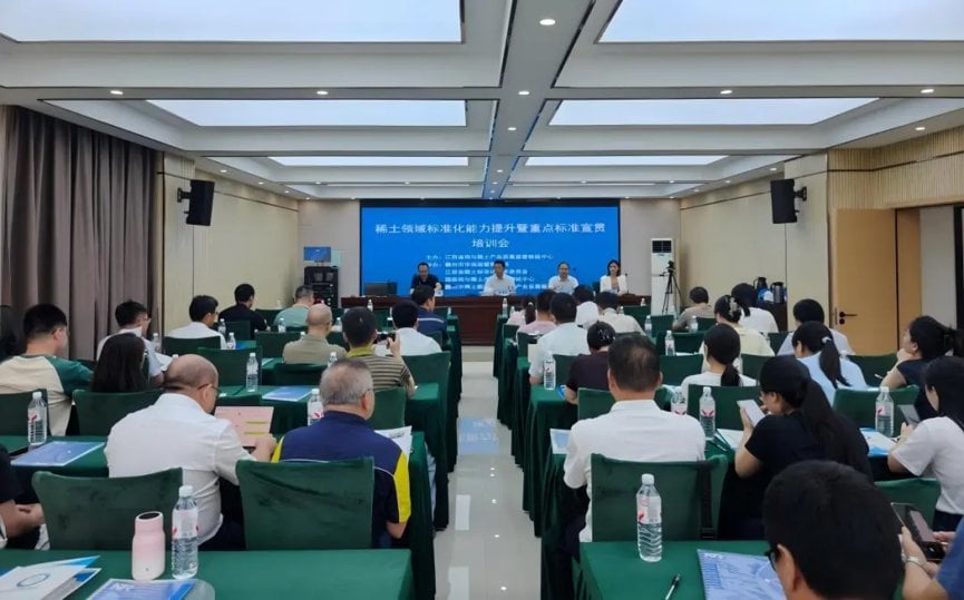 Attendees seated at green-draped tables during rare earth industry standardization training seminar with Chinese presentation