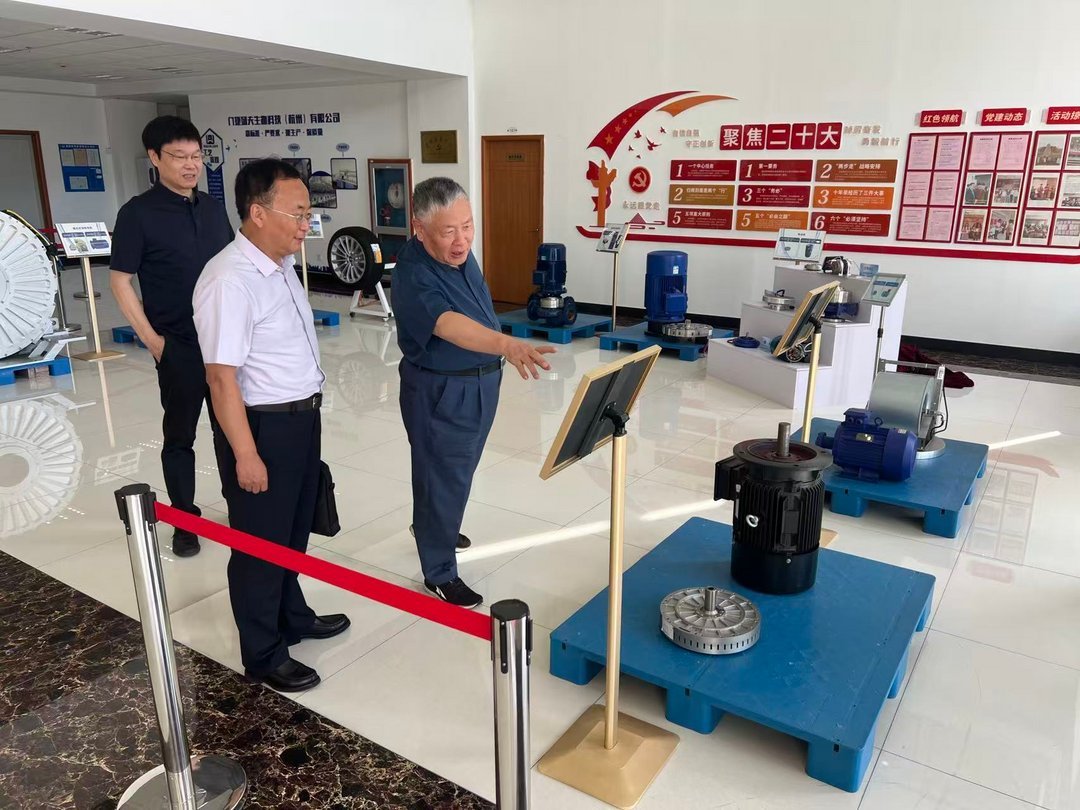 Three men in business attire examining industrial electric motors and pump equipment on blue pallets inside a Chinese manufac