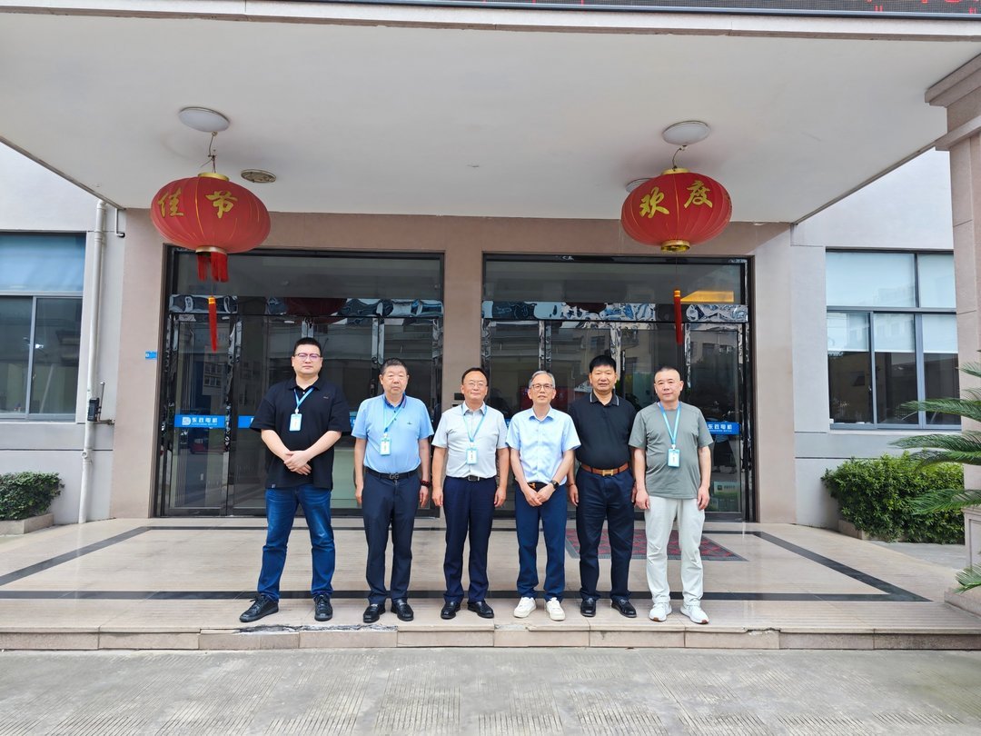 Six men in business casual attire standing before glass entrance doors decorated with red Chinese festival lanterns reading 隆