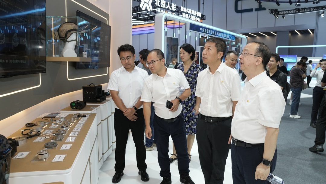 Chinese officials and executives at Beijing Humanoid Robot Innovation Center booth examining robotic components and AI techno