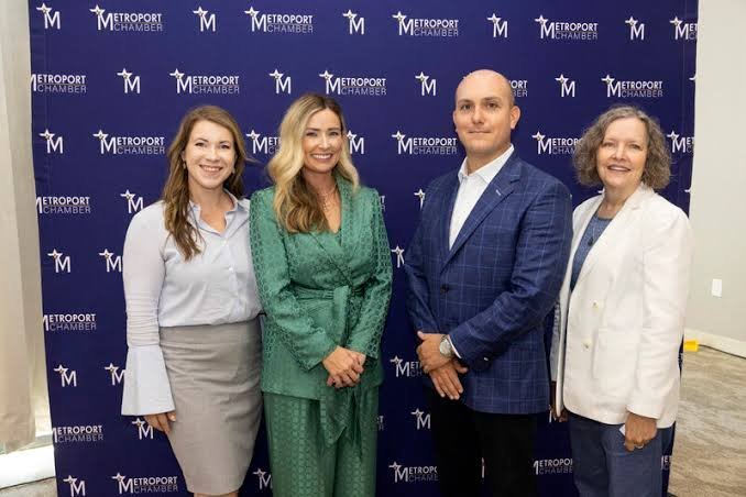 Four Metroport Chamber professionals, three women and one man in business attire, standing together at a Metroport Chamber br
