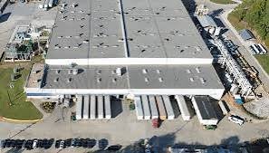 Bird's-eye view of a large industrial warehouse facility with multiple loading docks, semi-truck bays, rooftop HVAC units, an