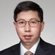Young East Asian man in charcoal gray suit and white dress shirt, professional corporate portrait with neutral background