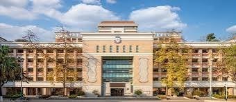 Embassy Suites Hotel with beige stone facade, large glass windows, and autumn trees flanking the multi-story entrance